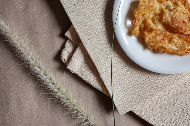 Omelette in un piatto bianco che viene posto su un panno marrone chiaro e l&#39;erba per la bellezza