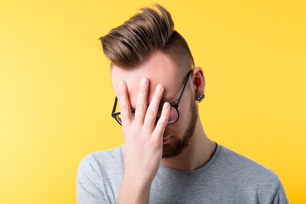 Omg wtf. Giovane stressato annoiato stanco che copre il viso con il palmo. Ragazzo sconvolto infastidito. Errore di disoccupazione perdita di lavoro.