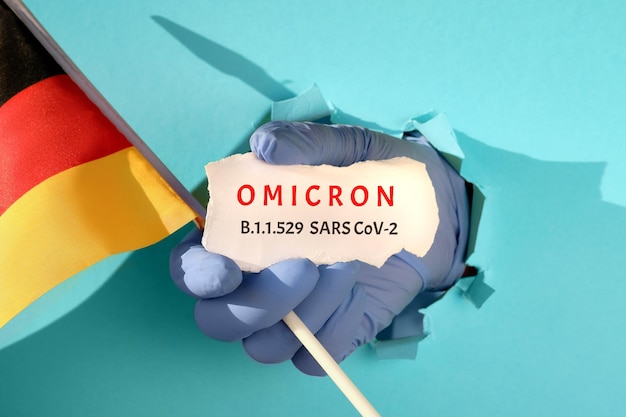 Omicron in germania nuova variante del virus corona di preoccupazione mano nel guanto da prese di carta strappata