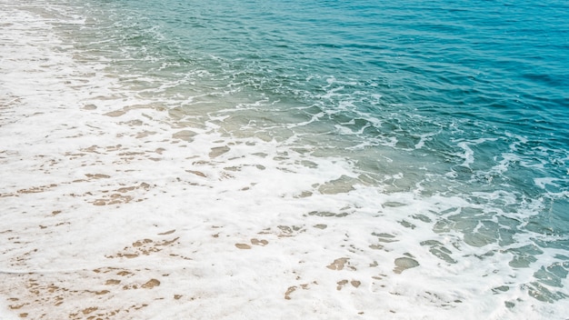 Onda dell'oceano blu sulla spiaggia sabbiosa.