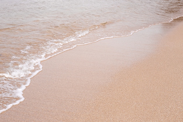 Onda di mare bella morbida sulla spiaggia sabbiosa. Trama di sfondo. Spiaggia di sabbia bagnata