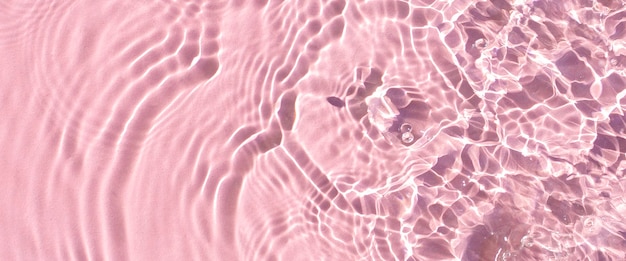 Onda di texture da gocce sull'acqua rosa sotto la luce del sole Banner piatto con vista dall'alto