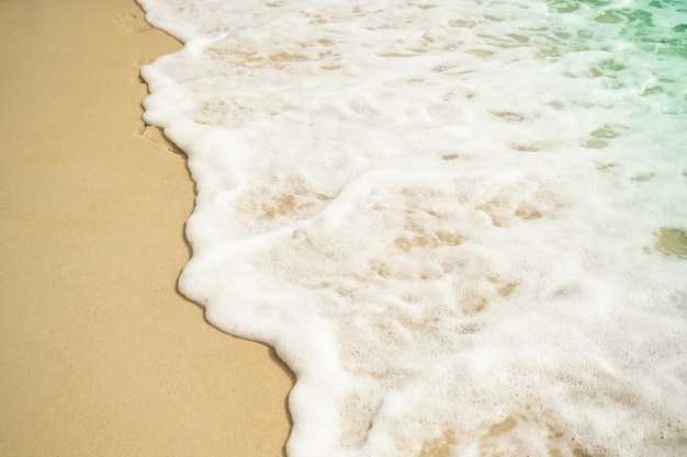 Onda morbida sulla spiaggia di sabbia alla costa con mare blu oceano natura tropicale turismo vacanza viaggio estate in vacanze bianco struttura carta da parati isola piatto lay