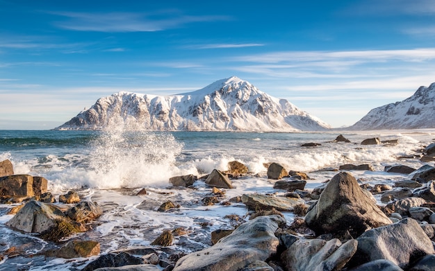 Onda oceanica artica che colpisce le rocce con la montagna del sole