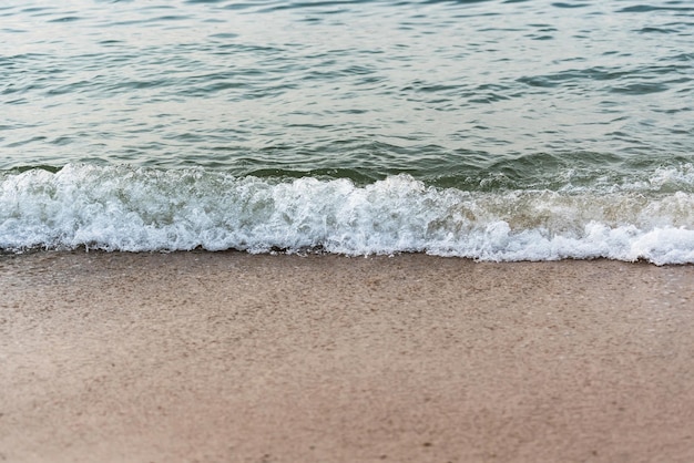 Onda sulla spiaggia sabbiosa al tramonto