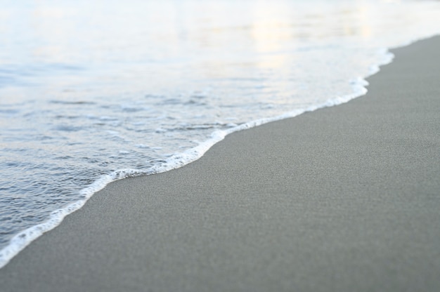 Onda vaga del mare sulla spiaggia di sabbia di sera