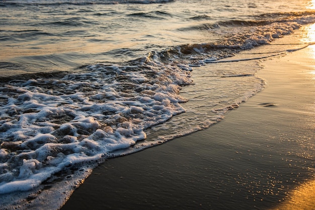 Onde che si avvicinano alla spiaggia sabbiosa durante il tramonto