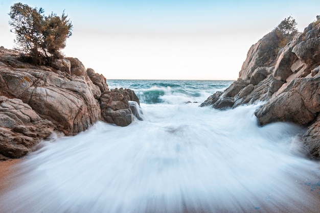 Onde che si infrangono contro gli scogli sulla spiaggia