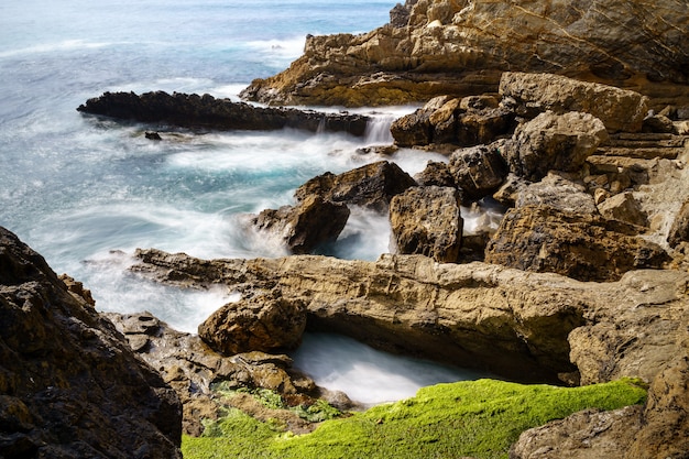 Onde che si infrangono contro le rocce della scogliera nella fotografia a lunga esposizione