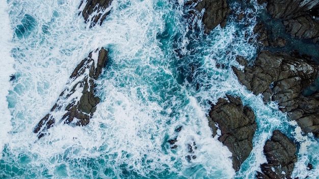 ONDE CHE SI infrangono SUGLI SCOGLI NEL MARE DELLA COSTA DEI PAESI BASCHI DA DRONE IN VISTA AEREA