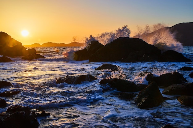 Onde che si infrangono sui massi sull'oceano durante il tramonto