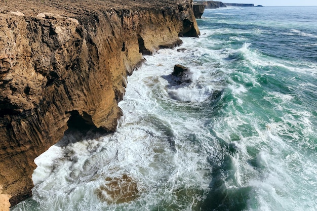 Onde che si infrangono sulla costa rocciosa. Vista dall'alto.