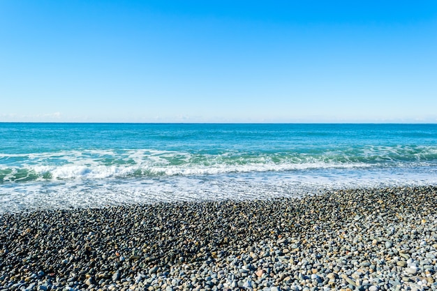 Onde del mare che si infrangono su una spiaggia sassosa, formando spruzzi e schizzi