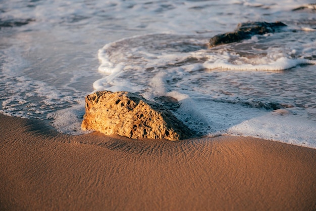 onde del mare spiaggia sabbia e pietra al tramonto
