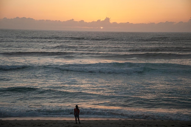 Onde del mare sulla spiaggia Ragazza che si gode il tramonto