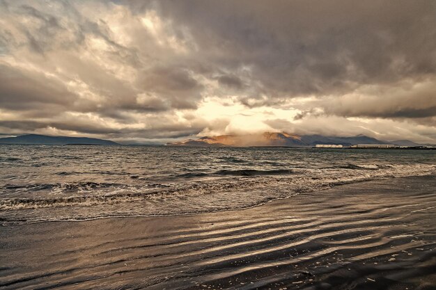 Onde del mare sulla spiaggia sabbiosa di Reykjavik in Islanda Paesaggio marino con acque grigie sul cielo nuvoloso Potenza della natura Wanderlust o viaggi e vacanze