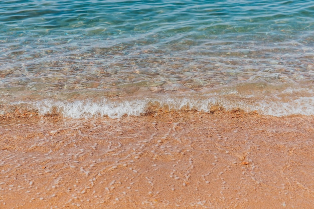 Onde del mare turchese che spruzza sulla riva di ghiaia