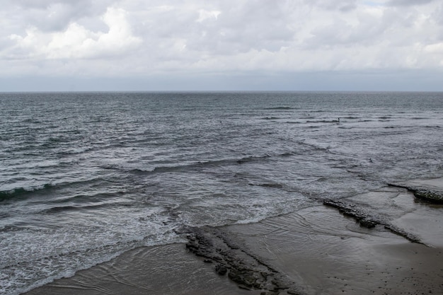 Onde della costa della spiaggia nuvolosa