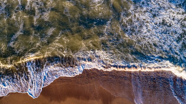 Onde di vista aerea sulla spiaggia di sabbia