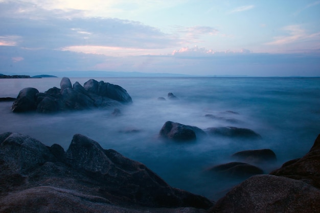 Onde lisce del mare blu la sera con pietra