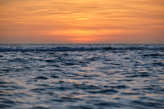 Onde rosse drammatiche dell'oceano al tramonto con acqua scura del mare di sera morbido