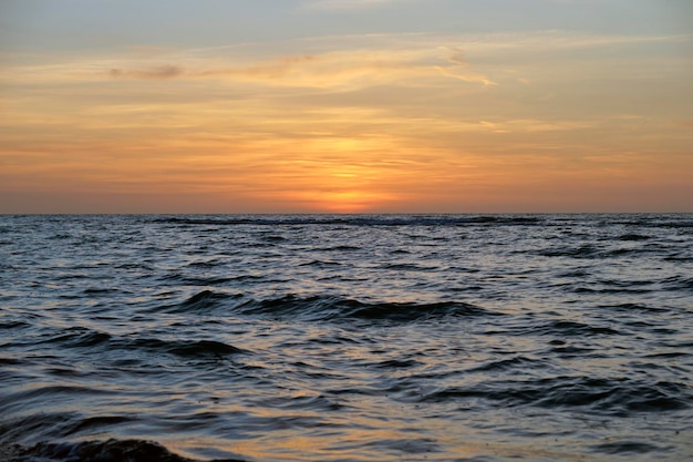 Onde rosse drammatiche dell'oceano al tramonto con acqua scura del mare di sera morbido