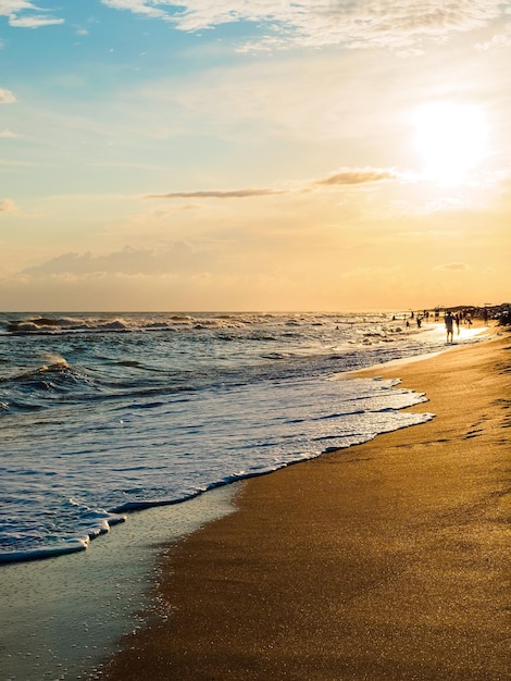 Onde spumose della spiaggia sabbiosa al tramonto bellissimo paesaggio