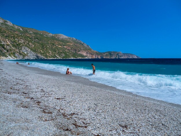 Onde spumose e turisti che fanno il bagno sulla spiaggia del Mar Egeo in Grecia