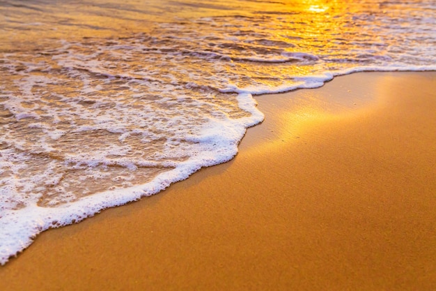 Onde sulla spiaggia ai tropici al tramonto