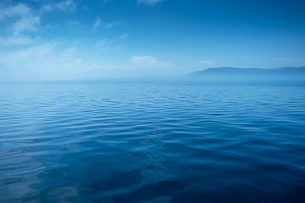 Onde sulla superficie dell'acqua con cielo nuvoloso e spazio copia montagna