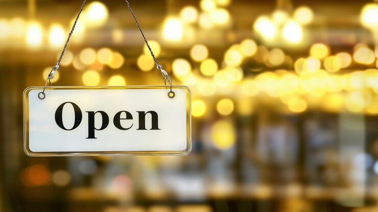 Open sign hanging in a storefront with a warm blurry background