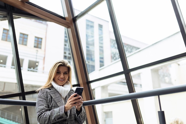 Operaia assicurativa femminile con un telefono cellulare in mano sullo sfondo di un edificio per uffici