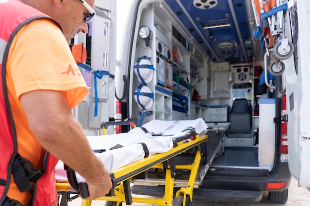 Operaio bagnino che lavora mentre afferra una barella su un'ambulanza