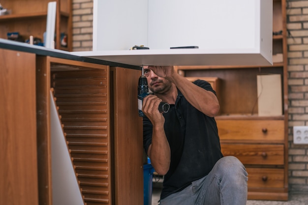 Operaio che pratica un foro sotto una tavola in un'officina