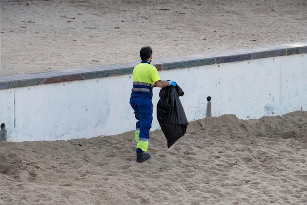 Operaio che raccoglie i rifiuti dalla spiaggia di sabbia