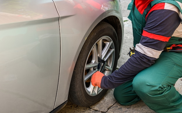 Operaio che ripara la ruota dell'auto con la chiave da vicino