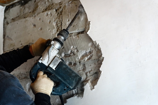 Operaio con martello demolitore che rimuove intonaco dal muro
