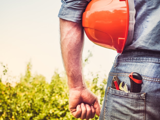 Operaio con strumenti e un casco arancione