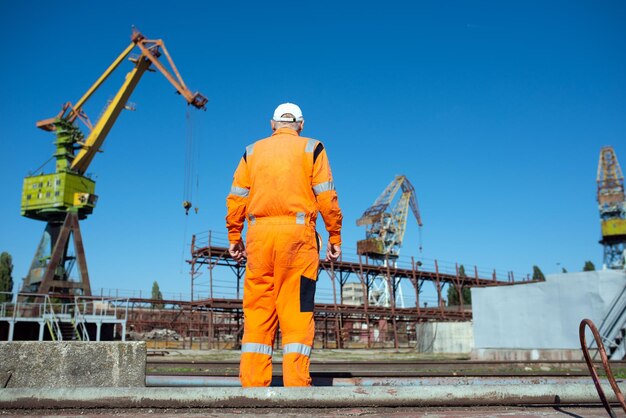 Operaio del cantiere navale sullo sfondo delle gru portuali