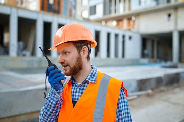 Operaio del costruttore che utilizza il walkie-talkie sul cantiere