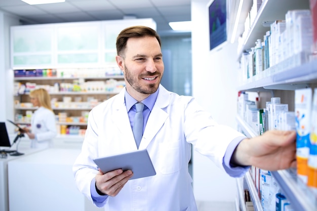 Operaio di farmacista maschio bello in camice bianco che lavora in farmacia o in farmacia.