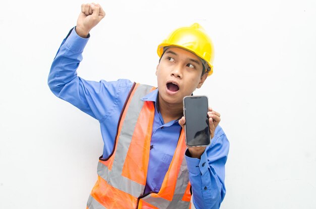 operaio edile asiatico che tiene un telefono con espressioni scioccate, sorprese e stupite.