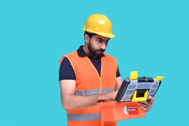 operaio edile che tiene in mano una cassetta degli attrezzi e la guarda modello pakistano indiano