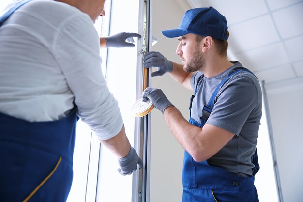 Operaio edile con tirocinante che installa finestra in casa