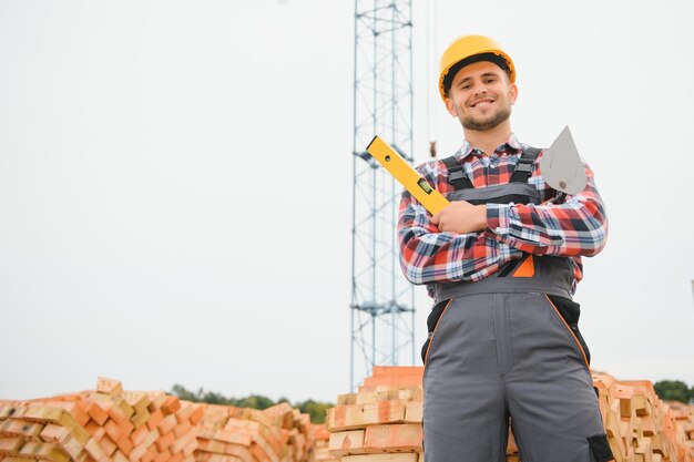 Operaio edile in uniforme e equipaggiamento di sicurezza ha un lavoro sulla costruzione di temi industriali