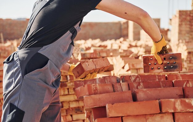 Operaio edile in uniforme e equipaggiamento di sicurezza ha un lavoro sulla costruzione