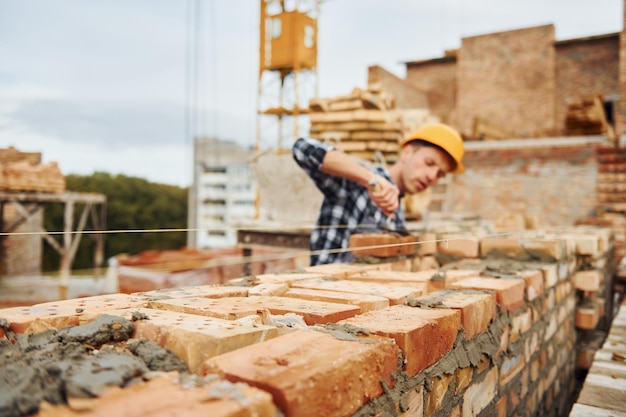 Operaio edile in uniforme e equipaggiamento di sicurezza ha un lavoro sulla costruzione