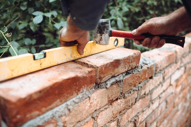 Operaio edile professionista che posa mattoni e costruisce muri di mattoni in un sito industriale Dettaglio della regolazione manuale bricksxA