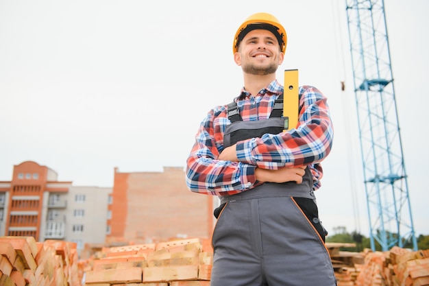 Operaio edile uomo in abiti da lavoro e un casco da costruzione Ritratto di costruttore maschio positivo in elmetto protettivo che lavora in cantiere