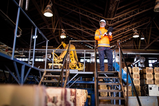 Operaio industriale con comunicazione radio che cammina attraverso la fabbrica di produzione industriale